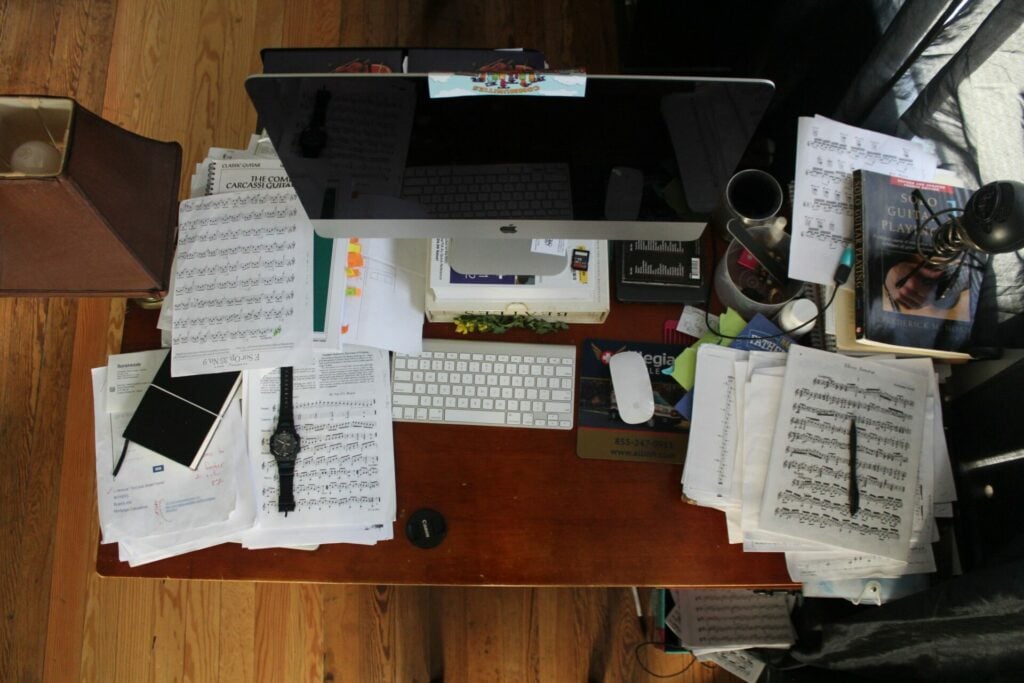 A messy desk with notes scattered across it. In the midst of the mess is a computer.
